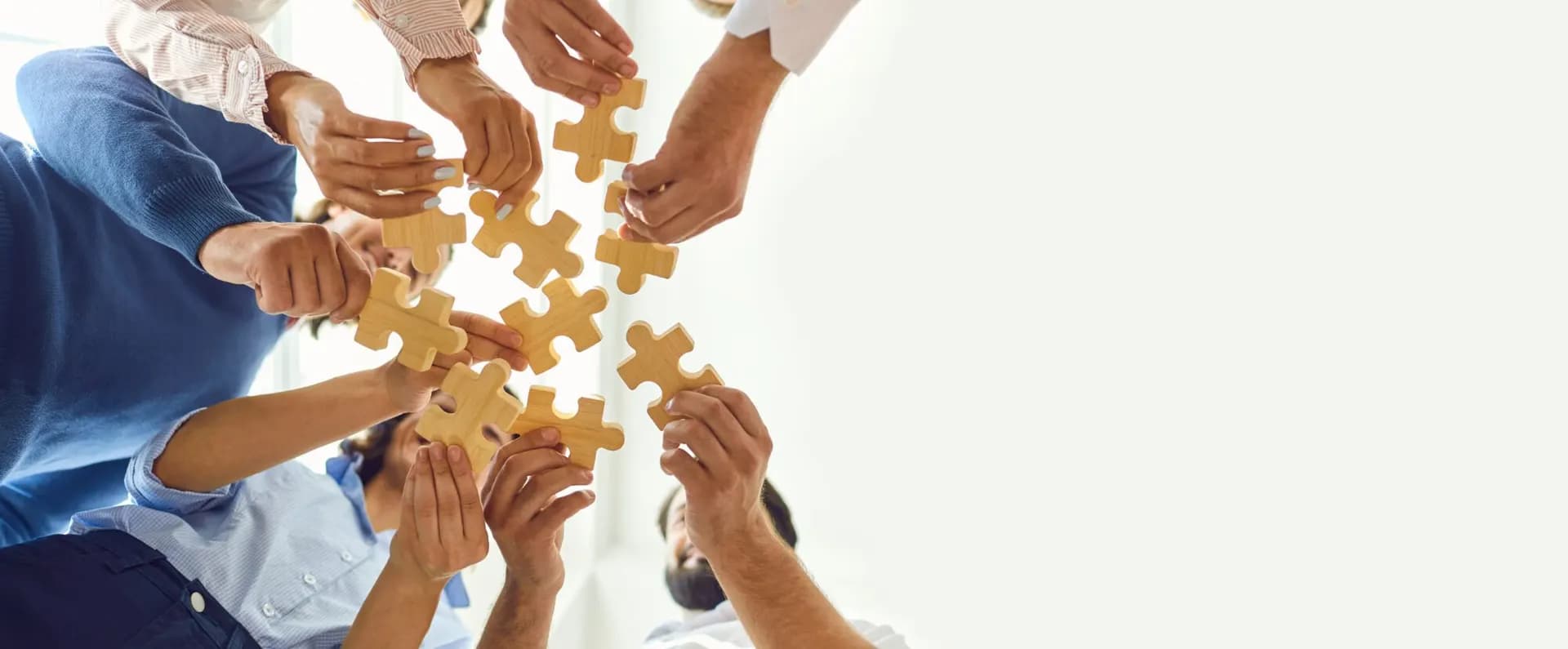 our team, Happy company employees joining parts of jigsaw puzzle during work meeting or team building activity